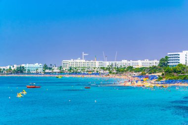 İnsanlar güneşli bir gün Agia Napa, Cypru adlı bir plajda tadını çıkarıyor