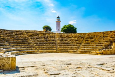 Paphos Archaeological Park Cypru üzerinde beyaz bir deniz feneri altında yer alan Roma Tiyatrosu