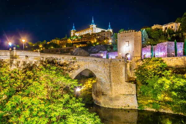 Night view of Alcantara bridge over river Tajo with Alcazar castle at background at Toledo, Spai