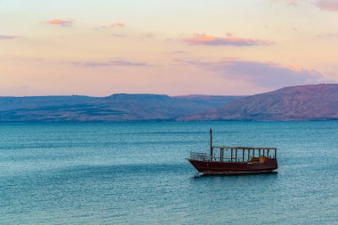 Celile Denizi üzerinde ISR yüzen bir ahşap tekne gün batımı görünümü