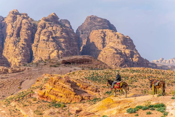 A man on a donkey is looking at Al Habis mountain behind Qasr al — Stock Photo, Image