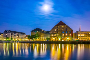 Danimarka'nın Kopenhag'ın merkezinde bir kanalın yanında binaların ve kurtarıcımızın kilisesinin gece görünümü.