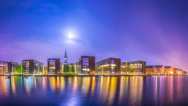 Danimarka'nın Kopenhag'ın merkezinde bir kanalın yanında binaların ve kurtarıcımızın kilisesinin gece görünümü.