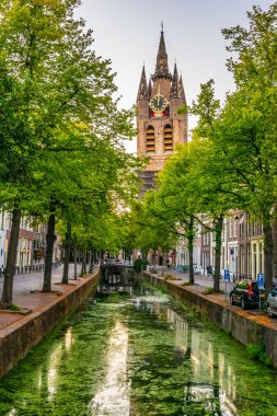 Delft, Nethe bir kanal arkasında Oude Kerk kilisenin Günbatımı görünümü
