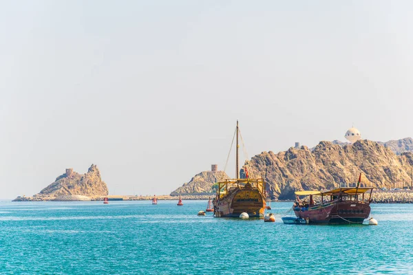 Um par de dhows - navios árabes tradicionais - está indo para o mar a partir de Muttrah parte do Mascate dominado por um forte em uma colina, Omã . — Fotografia de Stock