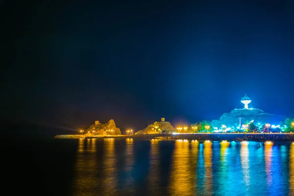 Night view of a peninsula in the Muttrah district in Muscat with the famous Al Riyam park and a watchtower on a steep cliff. — Stock Photo, Image