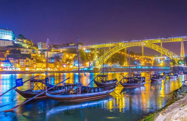 Vista noturna de barcos de madeira no Porto com ponte Luis I em fundo, portugal . — Fotografia de Stock