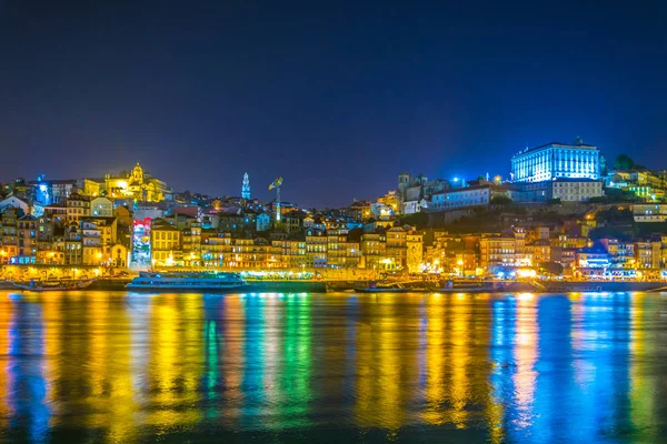 Vista nocturna de un palacio episcopal, torre dos clerigos y coloridas casas en Oporto, Portugal . — Foto de Stock