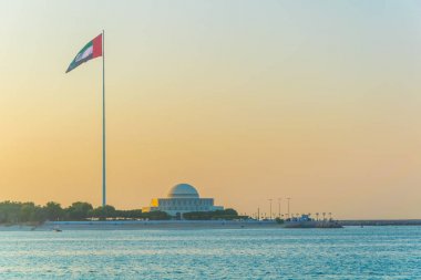 Abu Dabi'de gün batımında Birleşik Arap Emirlikleri ulusal tiyatro ile dev bir bayrak direği