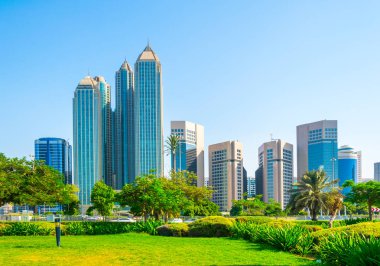 Abu Dabi'de yüksek gökdelenlerle dolu iş merkezinin yanında uzanan bir korniş in manzarası.