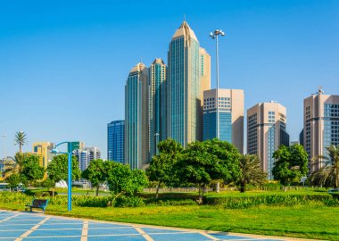 View of a corniche in Abu Dhabi stretching alongside the business center full of high skyscrapers. clipart