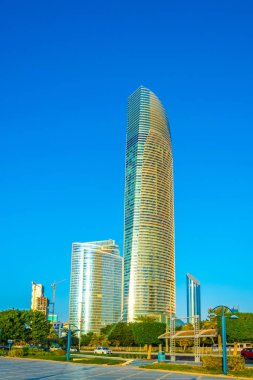 Abu Dabi'de yüksek gökdelenlerle dolu iş merkezinin yanında uzanan bir korniş in manzarası.