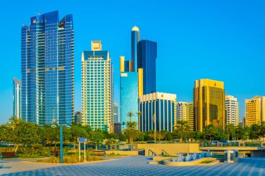 Abu Dabi'de yüksek gökdelenlerle dolu iş merkezinin yanında uzanan bir korniş in manzarası.