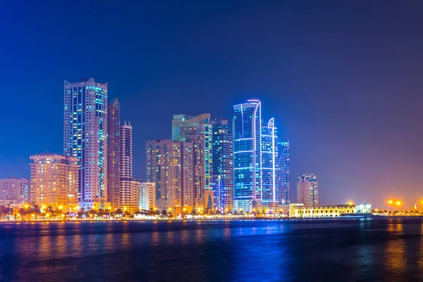 Rascacielos que rodean el anfiteatro Al Majaz situado en una isla artificial en Sharjah durante la noche, Emiratos Árabes Unidos — Foto de Stock