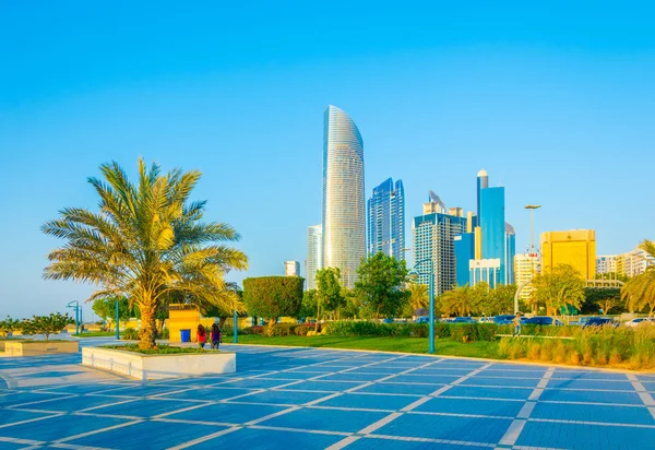 Blick auf eine Corniche in Abu Dhabi, die sich neben dem Geschäftszentrum voller hoher Wolkenkratzer erstreckt. — Stockfoto