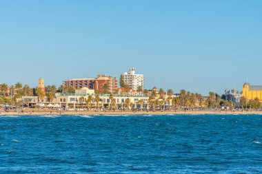 İnsanlar St. Kilda, Avustralya plajında güneşli bir günün tadını çıkarıyorlar.