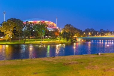 Adelaide ovalinin günbatımı Avustralya 'daki Torrens nehrinin arkasında görülüyor