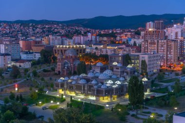 Kosova Ulusal Kütüphanesi ve Kosova 'nın Prishtina kentindeki bitmemiş Sırp Ortodoks İsa Kilisesi' nin günbatımı manzarası
