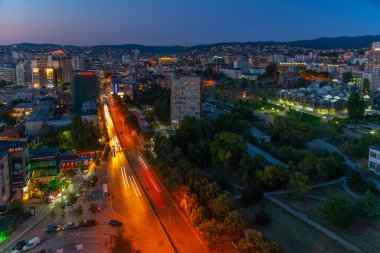 Kosova Ulusal Kütüphanesi ve Kosova 'nın Prishtina kentindeki bitmemiş Sırp Ortodoks İsa Kilisesi' nin günbatımı manzarası