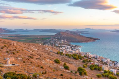 Sarande 'nin yırtık pırtık kıyı şeridi Arnavutluk' taki bir deniz fenerinin arkasında görülüyor