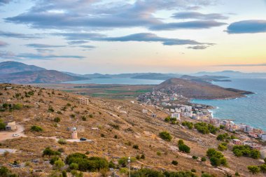 Sarande 'nin yırtık pırtık kıyı şeridi Arnavutluk' taki bir deniz fenerinin arkasında görülüyor