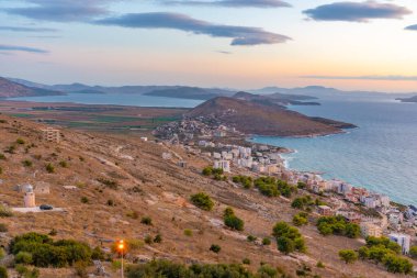 Sarande 'nin yırtık pırtık kıyı şeridi Arnavutluk' taki bir deniz fenerinin arkasında görülüyor