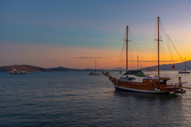 Arnavutluk 'un Sarande kentinde sahil kenarında demirleyen teknelerin gün batımı manzarası