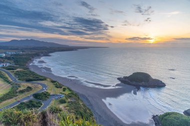 Yeni Plymouth yakınlarındaki Paritutu kayasından Yeni Zelanda kıyılarının günbatımı görüntüsü