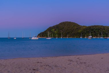 Yeni Zelanda 'daki Abel Tasman Ulusal Parkı' ndaki Torrent Koyu 'nda demirleyen teknelerin gün batımı görüntüsü