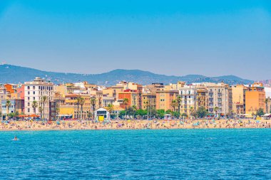 İnsanlar Barcelona, İspanya 'daki Barceloneta plajında güneşli bir günün tadını çıkarıyorlar.