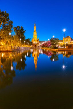 Plaza de Espana, İspanya 'nın Sevilla kentinde gece boyunca suya yansıdı.