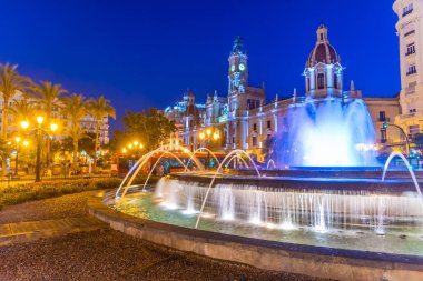 İspanya 'nın Valencia kentindeki bir çeşmenin arkasındaki belediye binasının gece manzarası.
