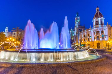 İspanya 'nın Valencia kentindeki bir çeşmenin arkasındaki belediye binasının gece manzarası.