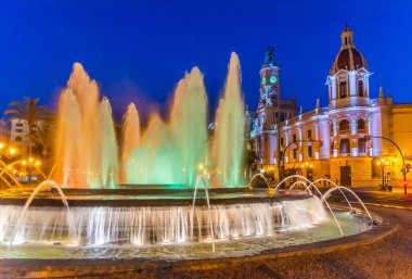 İspanya 'nın Valencia kentindeki bir çeşmenin arkasındaki belediye binasının gece manzarası.