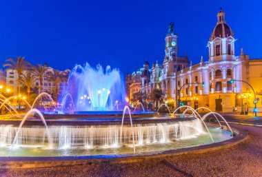 İspanya 'nın Valencia kentindeki bir çeşmenin arkasındaki belediye binasının gece manzarası.