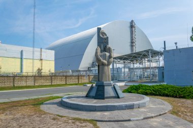 Containment area of Chernobyl power plant viewed behind a memorial in the Ukraine clipart