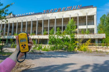 PRIPYAT, UKRAINE, AĞUSTOS 30 Ağustos 2019: Ukrayna 'daki Pripyat' ta kültür evinin önünde bir geiger sayacı tutan kadın