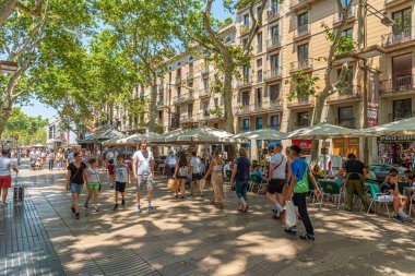 BARCELONA, SPAIN, JUNE 30, 2019: People are strolling at La Rambla street in Barcelona, Spain clipart