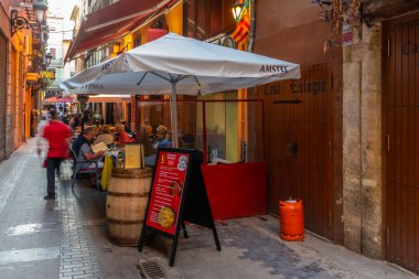 VALENCIA, İspanya, 17 Haziran 2019: İnsanlar Valencia, İspanya 'nın merkezinde dar bir sokakta yemek yiyorlar.