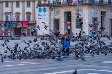 MILANO, İtalya, 20 HAZİRAN 2019: Kişi Milano, İtalya 'daki Piazza del Duomo' da güvercinleri besliyor