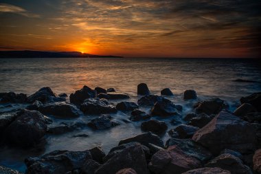 Denizin dalgaları ile üzerinde dramatik günbatımı