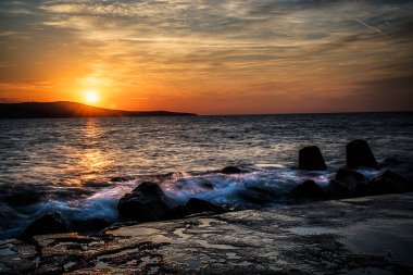 Denizin dalgaları ile üzerinde dramatik günbatımı