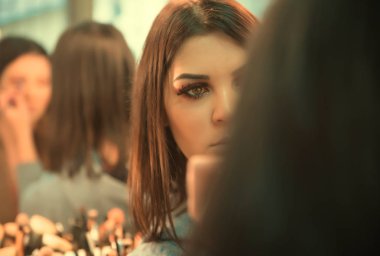 Güzel kız uygulanan makyaj ve ayna önünde ayakta