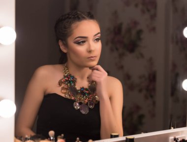 Genç kız makyaj uygulayarak aynaya bakıyor