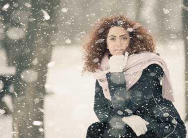 Kırmızı kıvırcık saçlı güzel kız kar düşüyor gibi poz