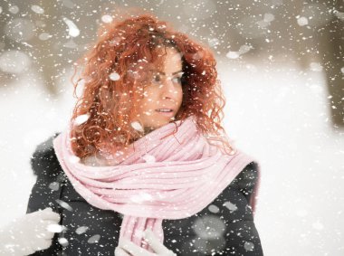 Kırmızı kıvırcık saçlı güzel kız kar düşüyor gibi poz