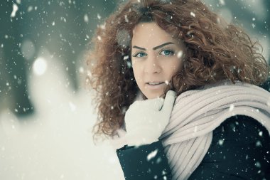 Kırmızı kıvırcık saçlı güzel kız kar düşüyor gibi poz