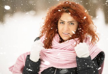 Kırmızı kıvırcık saçlı güzel kız kar düşüyor gibi poz