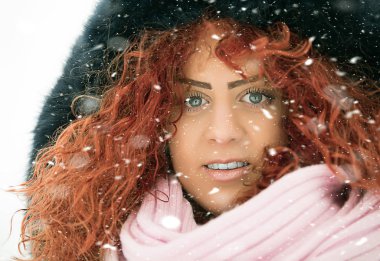 Kırmızı kıvırcık saçlı güzel kız kar düşüyor gibi poz