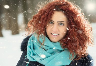 Kırmızı kıvırcık saçlı güzel kız kar düşüyor gibi poz